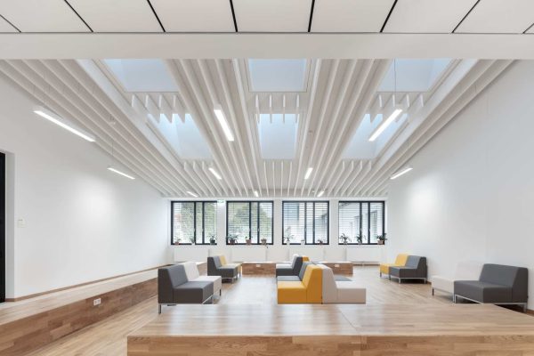 Ecophon Solo Baffeln setzen architektonische Akzente an der Decke eines hellen Raums mit modernen Sitzmöbeln.