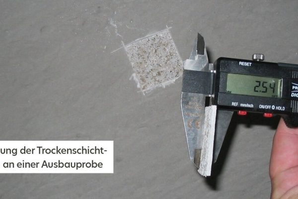 Präzise Messung der Trockenschichtdicke an einer Ausbauprobe mit einem digitalen Messschieber zur Qualitätskontrolle.