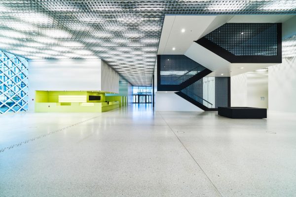Modernes Foyer im Futurium Berlin mit geometrischer Decke, schwarzer Treppe und hellem Boden.