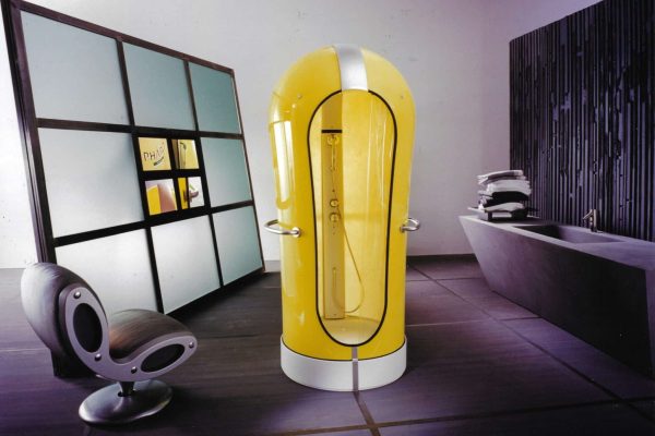 Gelbe kapselförmige Duschkabine PHARO Cocoon in einem minimalistischen Badezimmer mit modernem Designer-Sessel.