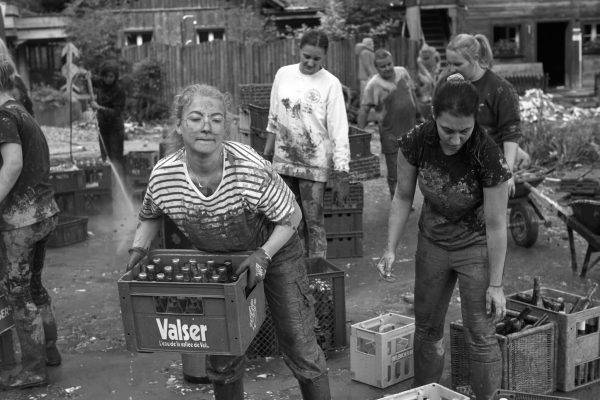 Schlammbedeckte Helfer bergen Valser Getränkekisten bei der Sanierung nach Unwetter im Hotel an der Emme.