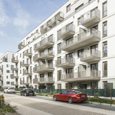 Straßenansicht der Wohnanlage PP49 mit rhythmisch angeordneten Balkonen und klarer Fassadengliederung.