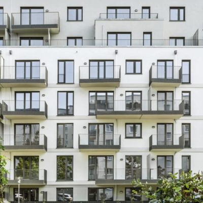 Frontale Ansicht der Wohnfassade mit übereinander angeordneten Balkonen und großflächigen Fensteröffnungen.