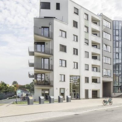 Gebäudeecke des Projekts PP49 mit markanter Höhenstaffelung und Erdgeschosszugang an der Hauptstraße.