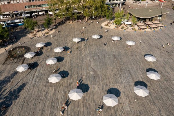 Luftaufnahme vom Sechseläutenplatz Zürich mit kreisförmig angeordneten weißen Sonnenschirmen und Passanten.