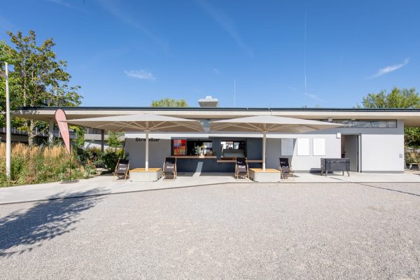 Moderne Strandbar im Seebad Neuer Strand Breitenbrunn Neusiedlersee mit Sonnenschirmen und Ahoi-Liegestühlen.