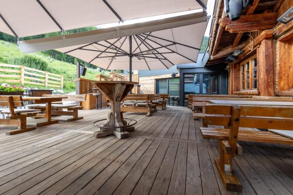 Sonnenschirm PALAZZO Royal mit Regenrinne auf einer rustikalen Holzterrasse vor einer alpinen Bergkulisse.