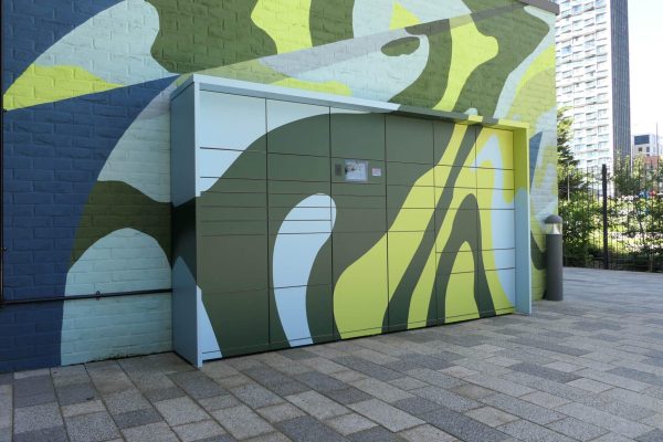 Bunte myRENZbox Paketkastenanlage mit Camouflage-Muster an einer Wand des Imperial College in London.