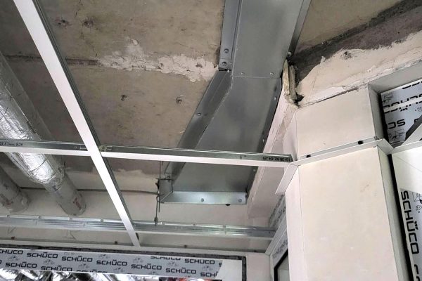 Verzinkte Reduzierung am Lüftungskanal unter einer Betondecke im modernen Industrie-Rohbau.