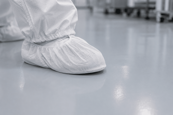 Person mit Überschuhen auf glatten Reinraumbodenlösungen für maximale Sauberkeit und effektive Kontaminationskontrolle.