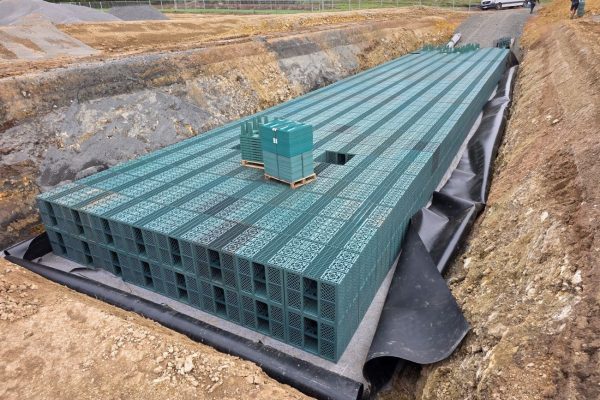 Grüne Speichermodule der RigoCollect Regenwasserrückhaltung ESN in einer mit Folie ausgekleideten Baugrube.