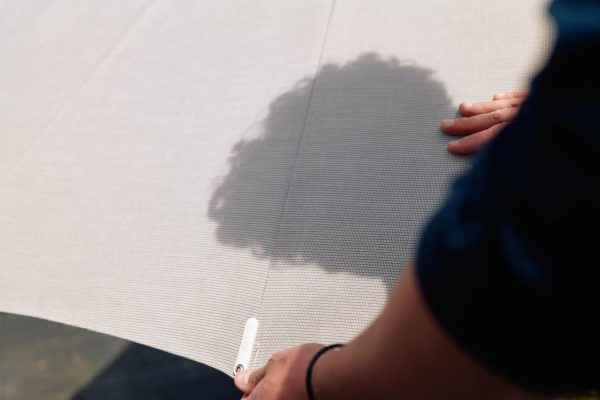 Hände halten den hellen Stoff eines Glatz Sonnenschirms, der durch hochwertigen UV-Schutz überzeugt.