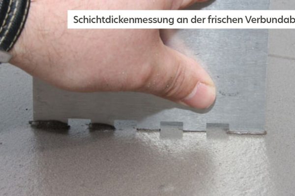 Hand führt eine Schichtdickenmessung an der frischen Verbundabdichtung mit einem Messkamm zur Kontrolle durch.
