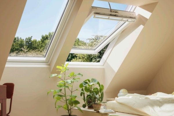 Geöffnetes elektrisches 230 V Schwingfenster im hellen Dachzimmer mit Pflanzen und weitem Ausblick.
