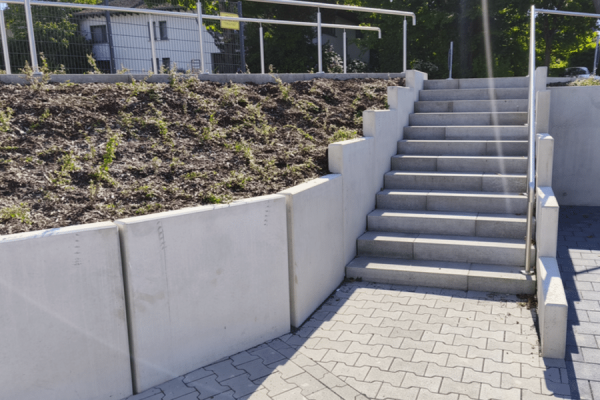 Stützwinkel in der Treppengestaltung sichern die Böschung neben einer Außentreppe aus Betonfertigteilen.