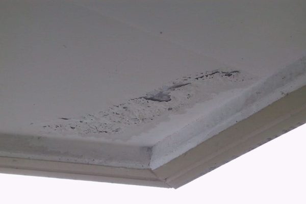 Abblätternder Farbanstrich an der Kragplatten-Untersicht mit deutlicher Verwitterung und Materialschäden.