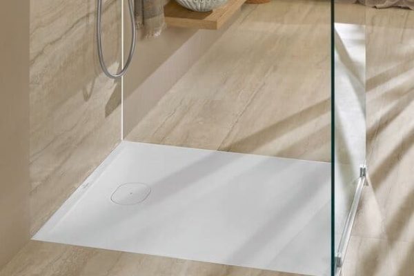 Modernes Ecora Hotelbad mit bodenebener weißer Duschwanne, Glaswand und beigen Fliesen in zeitlosem Design.