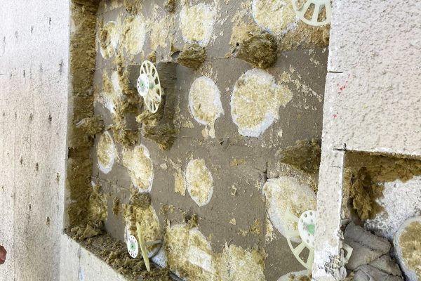 Probeöffnung nach Hinterfüllung mit Verklebung von Dämmplatten und Dämmstoffhaltern an einer Fassade.