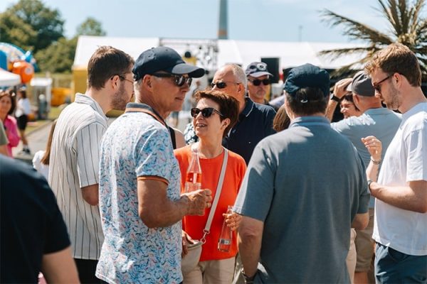 Mitarbeiter feiern ein fröhliches Sommerfest mit Familie und Freunden bei strahlendem Sonnenschein im Freien.