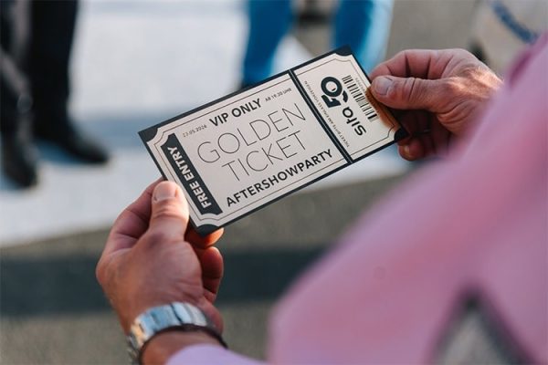 Hände halten ein Golden Ticket als Einladung zur Aftershowparty für das SitaTeam zum 50. Firmenjubiläum.