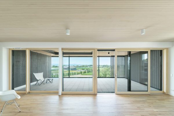 Moderne Innenansicht mit geschlitzter Decke BLT BOX FS, hellem Holzparkett und großen Glasfronten.