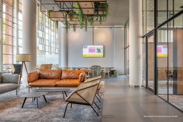 Modernes Büro am Johanna Westerdijkplein 75 mit Ledersofa, Flechtstühlen und hängenden Pflanzen.