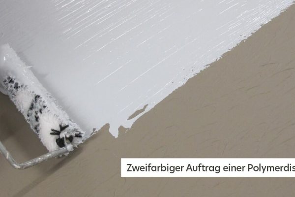 Zweifarbiger Auftrag einer Polymerdispersion mit einer Malerrolle auf einen grauen Bodenbelag.