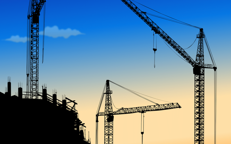 Großbaustelle im Hochbau mit Baukränen bei Sonnenuntergang