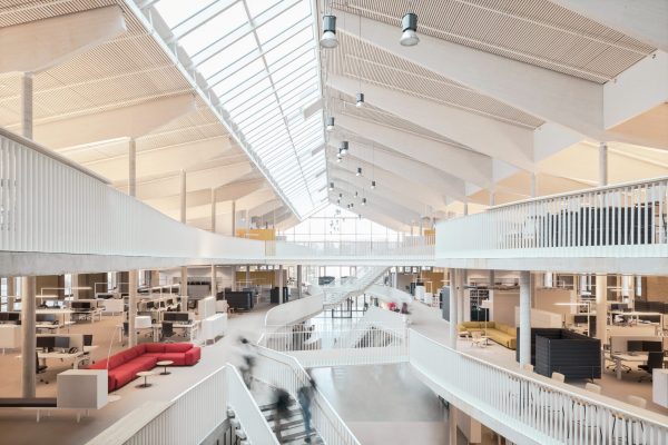 Modernes, lichtdurchflutetes Atrium im Alnatura Campus Darmstadt mit offenen Büroflächen und markanter Holzdecke.