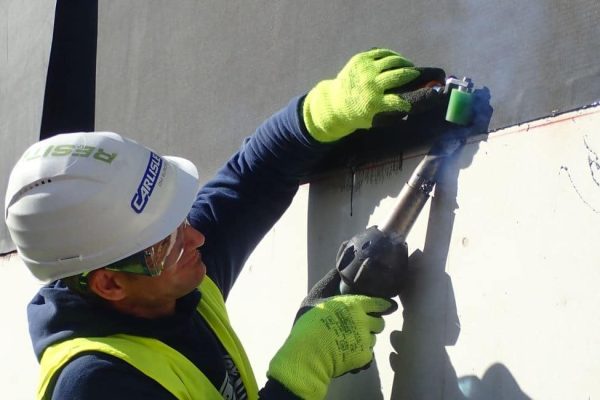 Handwerker nutzt ein Heißluftgerät für die praxisgerechte Bauwerksabdichtung mit Carlisle-Systemlösungen.
