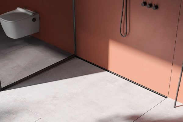 Schmale schwarze TECEdrainway Duschrinne im modernen Bad mit terracottafarbenen Wänden und minimalistischem Design.