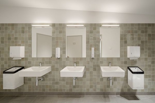 Stilvolle Sanitärräume im Sensoria mit modernen Waschbecken vor einer markanten grünen Fliesenwand.