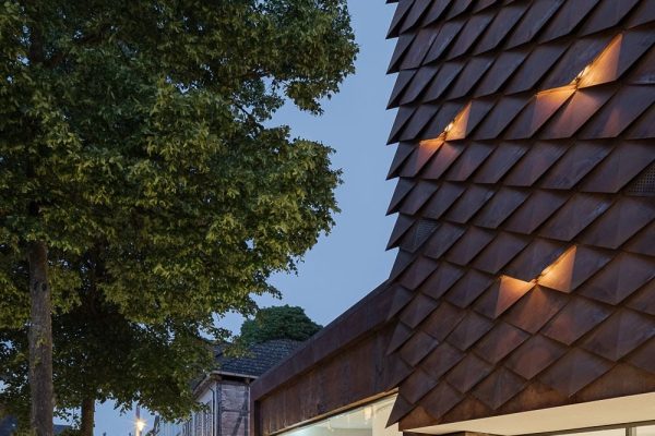Moderne Schindelfassade des Sensoria Museums in Holzminden mit großen Glasfronten in der Abenddämmerung.