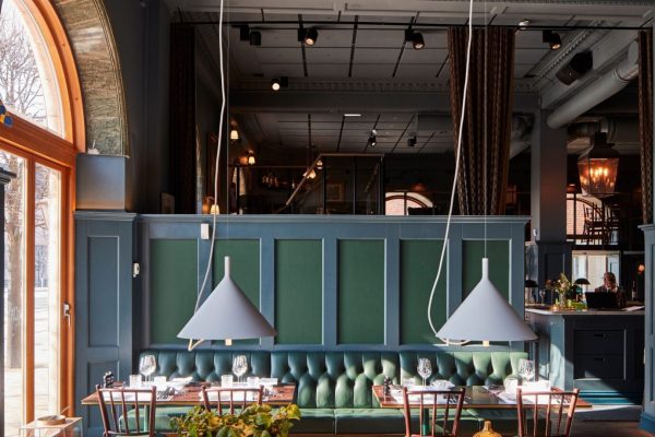Grüne Ecophon Texona Wandabsorber in Deep Forest hinter einer Sitzbank in einem modernen Restaurant.