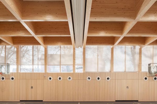Durach E-203-BS Ballwurfsicheres Rollo in einer modernen Sporthalle mit markanter Holzdeckenkonstruktion.
