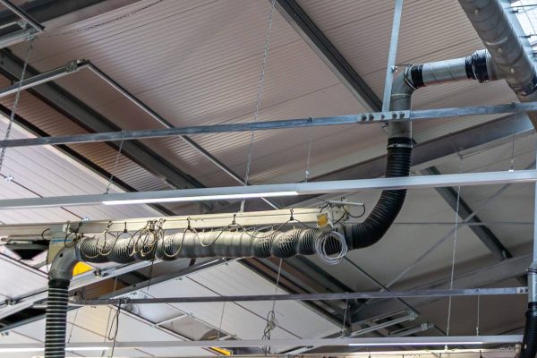 Abgasabsauganlage statisch berücksichtigt mit flexiblen Schläuchen an der Decke einer Fahrzeughalle.