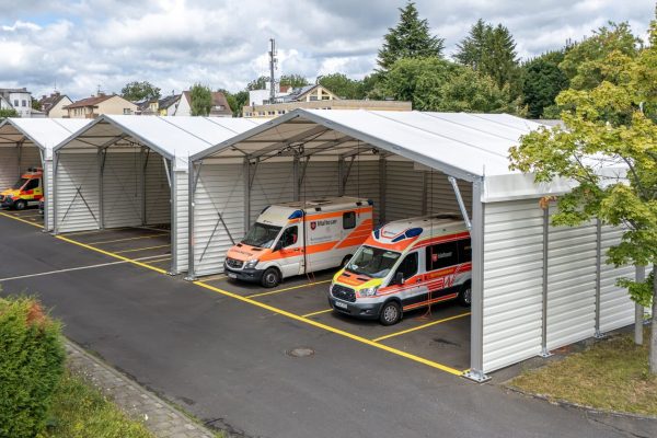 Weiße Fahrzeughalle für Ambulance Wiesbaden und Malteser mit mehreren Rettungswagen in den Stellplätzen.