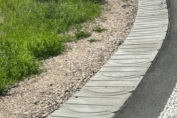 Bankettplatten zur stabilen Befestigung des Straßenrands an einer asphaltierten Kurve im Einsatz.