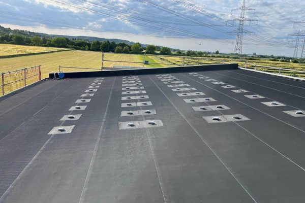 Fertiggestellte Flachdach-Abdichtung als Dachbahn-System mit stabilen Halterungen für eine moderne Solaranlage.