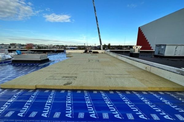 Konstruktiver Aufbau von Flachdachsystemen mit Dämmplatten auf einer blauen Alutrix-Dampfsperrbahn.