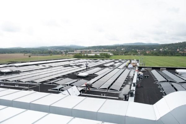 Montage einer Photovoltaik-Anlage sowie technische Aufbauten und Systeme auf dem Flachdach einer Industriehalle.