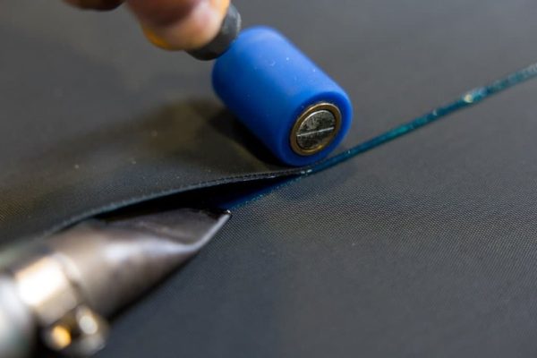 Heißluftverschweißung einer EPDM-Dachbahn mit einem Handschweißgerät und einer blauen Andrückrolle.