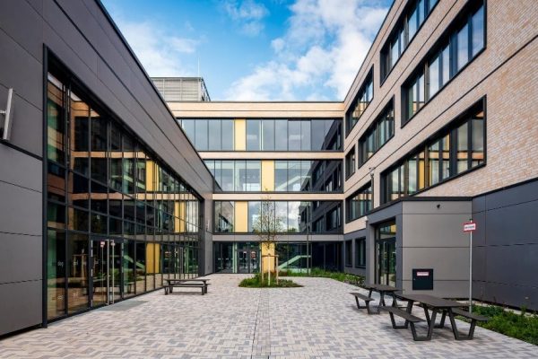 Transparentes Verbindungsbauwerk mit Marktplatz und Mensa im modernen gepflasterten Innenhof eines Bürokomplexes.