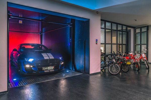 Blauer Sportwagen auf einem fugenlosen Steinteppich in einer exklusiven Garage mit moderner Mancave-Optik.