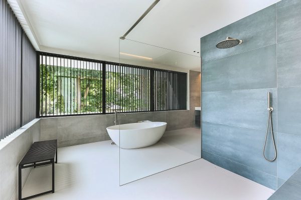 Modernes fugenloses Badkonzept mit hellem Designboden, freistehender Wanne und Glasdusche in hochwertiger Optik.