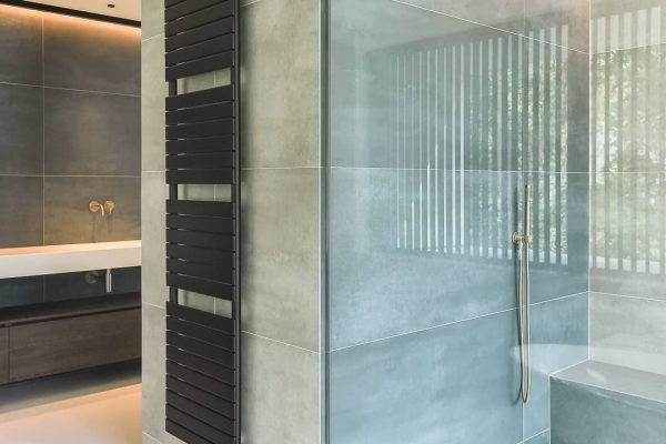 Modernes Badezimmer mit fugenlosen Flächen im Duschbereich und großformatigen Fliesen für eine klare Optik.