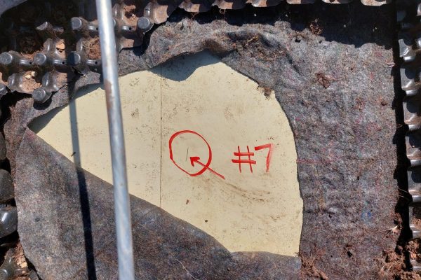 Markierte mechanische Beschädigung an einer Kellerabdichtung unter Noppenbahn und Schutzvlies.