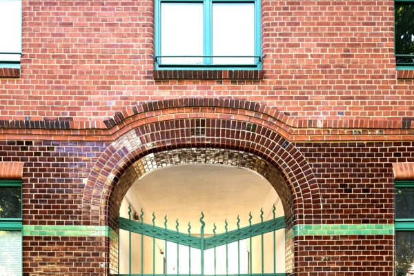 Backsteinfassade mit grünem Bogentor und Fenstern bei der Aufstockung Mehrfamilienhaus in Hamburg.