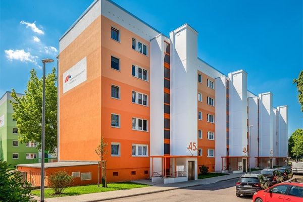 Modernisierter Wohnungsbau in Bernburg mit orangefarbener Fassade und modernen Gen2 Genesis Aufzugstürmen.