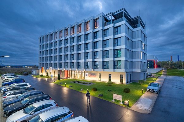 Modernes Frames Hotel in Mülheim-Kärlich mit Gen360 Aufzugstechnologie in der Abenddämmerung.